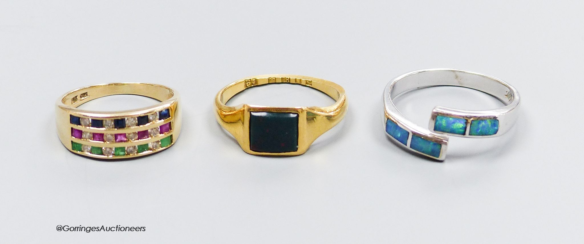 An 18ct white gold and opal ring, size Q, gross 4g, an 18ct gold and bloodstone ring, size O, gross 3g, and a 14k gold, sapphire, emerald, ruby and diamond ring, size L, gross 3g.